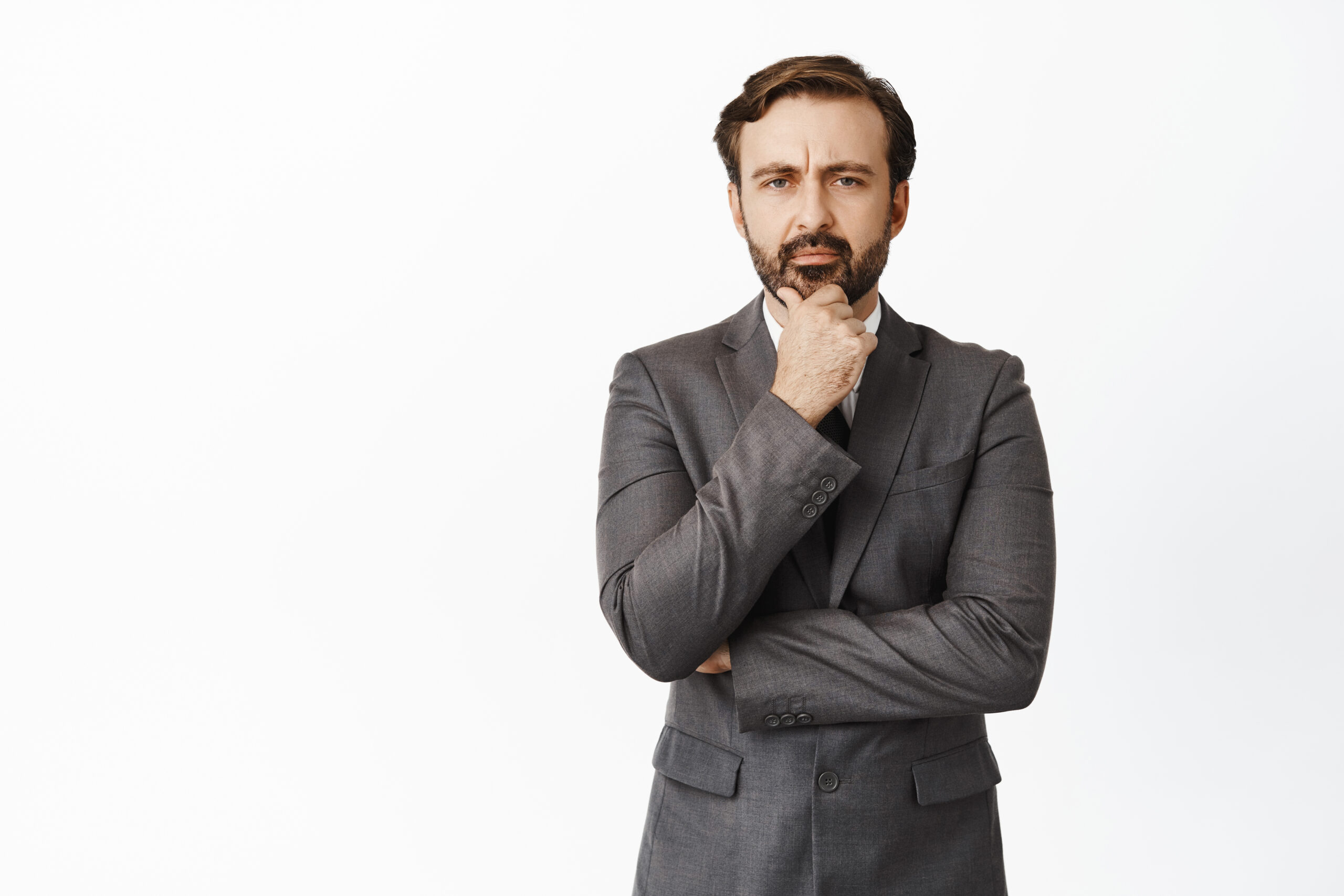 portrait of serious businessman touching his beard, frowning and thinking, making important decision, ponder, standing over white background